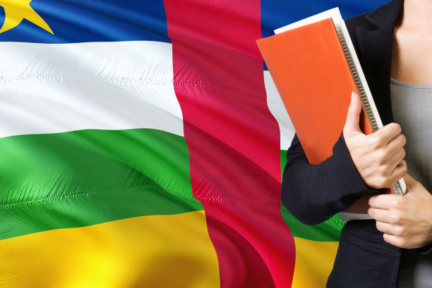 学习非洲语言概念。一名年轻女子站在中非共和国国旗的背景下。老师拿着书，橘黄色的空白书封面。图片下载