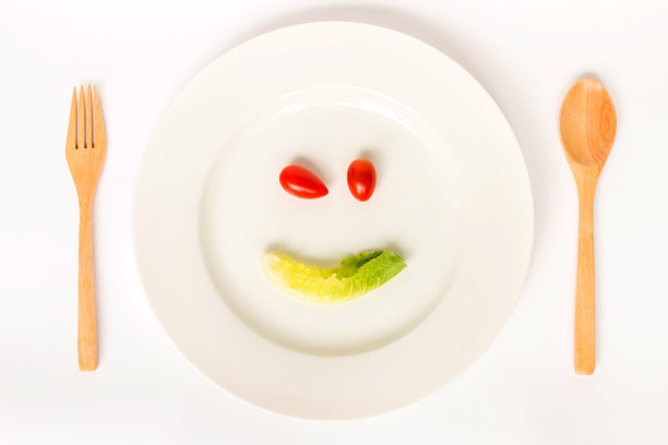 用蔬菜做成的笑脸放在盘子里。图片下载
