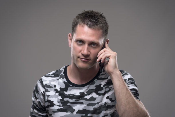 英俊的年轻成年男子的肖像讲手机和微笑看着镜头图片下载