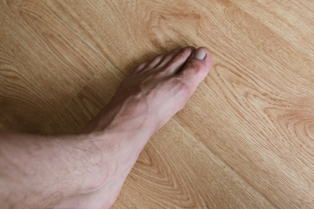疲惫的人的脚站在木地板上。照片上有静脉和脚趾。图片下载