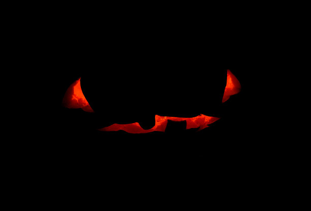 万圣节南瓜吓人的脸和蜡烛里面，概念照片上的黑色背景。南瓜脸发光的轮廓。图片下载