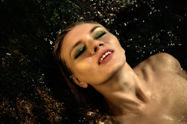 近距离肖像的模特与明亮的化妆在水。水背景上的金发碧眼美女图片下载