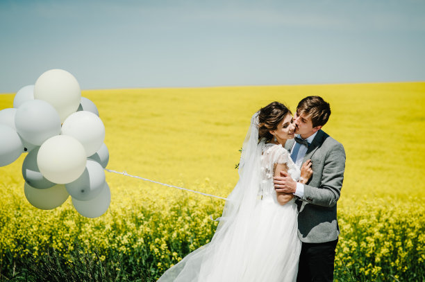 婚礼结束后，幸福的新娘和新郎拿着气球站起来。一对新婚夫妇在乡村公路上度蜜月，拥抱亲吻。照片。图片下载