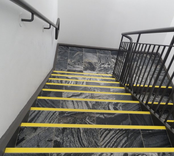 沿着灰色和黑色的大理石楼梯往下走，每一级都贴着黄色的胶带图片下载