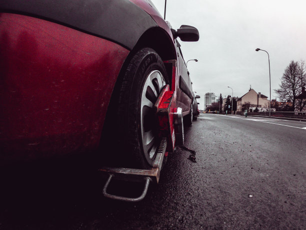 用一个特殊的红鞋锁住汽车。锁轮车在禁止停放的地方。图片下载