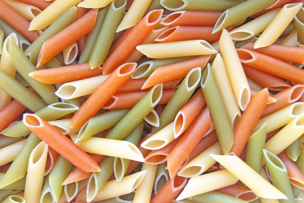 质感的意大利食物背景-彩色的生通心粉在木桌上图片下载