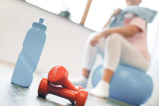 老年妇女在家锻炼，坐在健身球近距离图片下载