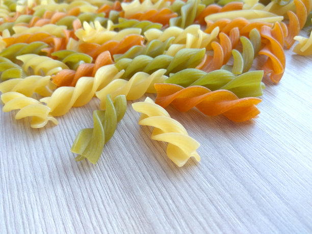 质感的意大利食物背景-彩色的生意大利面在木桌上图片下载