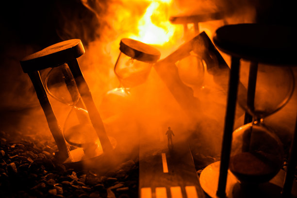 时间的概念。一个男人的剪影站在沙漏中间，在黑暗的背景上有烟雾和灯光。超现实主义的装修图片图片下载