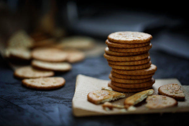 一堆圆圆的咸脆饼干放在黑色的背景上。茶的美味。选择性对焦，深色食物照片，低调图片下载
