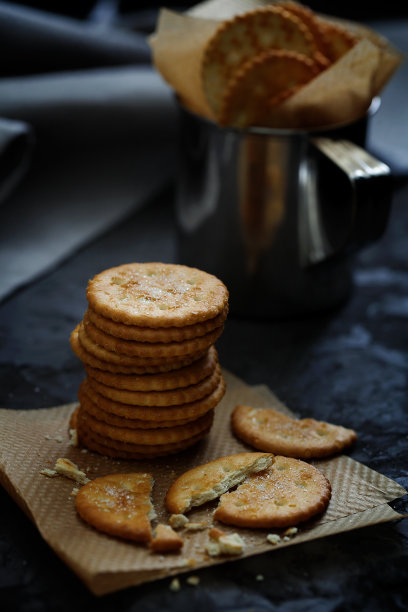 一堆圆圆的咸脆饼干放在黑色的背景上。茶的美味。选择性对焦，深色食物照片，低调图片下载