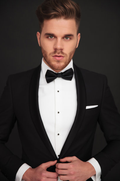 年轻的新郎看着镜头，扣上他的外套图片下载