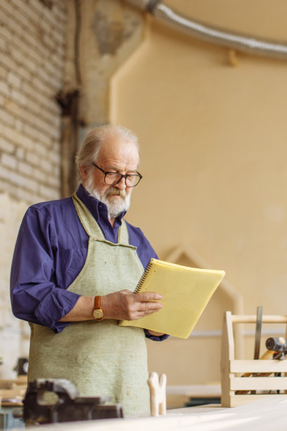 近景拍摄的老人拿着练习本在他的工作室图片下载