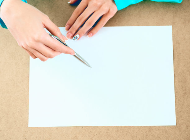 白纸躺在桌子上，等待着点子，女人的手在上面。图片下载