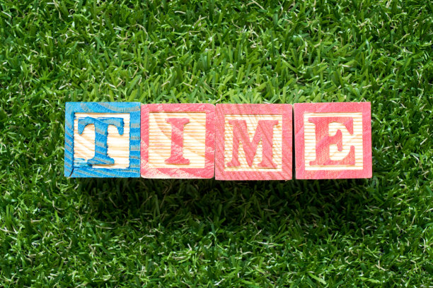 彩色木块在文字时间上以人工绿草为背景图片下载