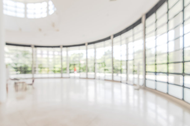 酒店或写字楼大堂的背景模糊的内部景观，面向接待大厅，现代豪华的白色房间空间与模糊的走廊和建筑玻璃墙窗户图片下载