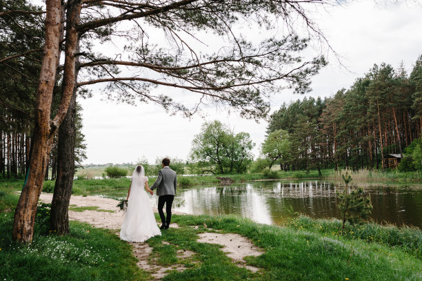 一个迷人的新郎和新娘在公园的自然中走回来的肖像。幸福快乐的时刻。一对浪漫的新婚夫妇在池塘边。在湖边举行婚礼。摄影。照片。图片下载