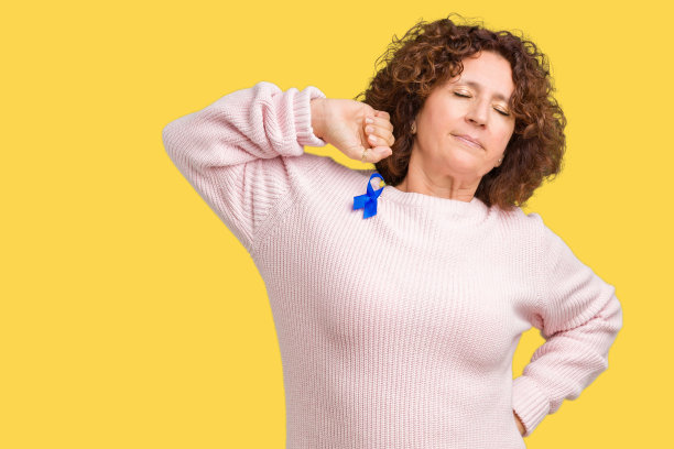 中年年长妇女穿着多变的蓝色缎带意识在孤立的背景伸展，疲倦和放松，困倦和打哈欠的清晨图片下载