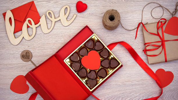 木质背景上有心形巧克力糖果的情人节礼物盒图片下载