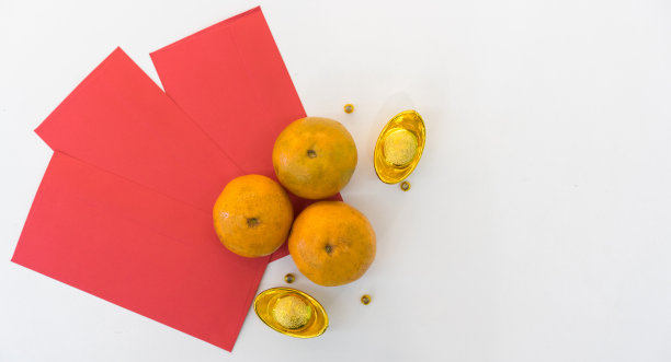 在白色的桌子上放上带有金元宝和红包袋的桔子，以体现中国新年的传统和文化理念图片下载