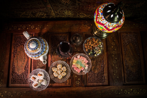 阿拉伯茶在玻璃和东方小吃在复古的木制表面。东方茶的概念。低灯光休息室内部地毯。空的空间。图片下载