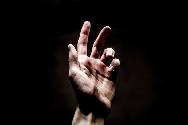 在黑暗的背景上，一只手伸向灯光图片下载