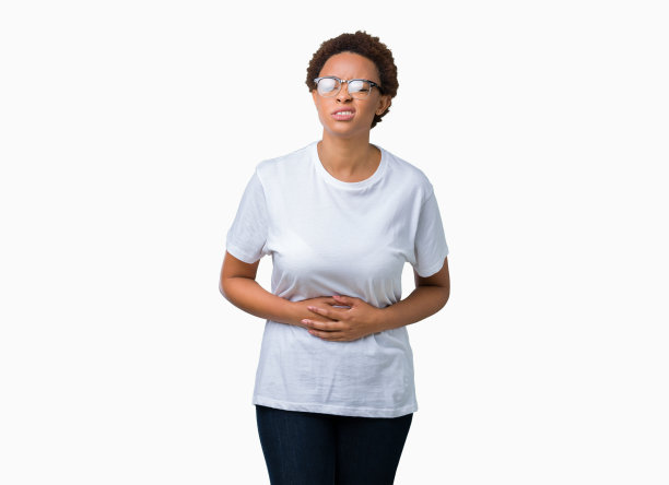 美丽的年轻非洲裔美国妇女戴眼镜在孤立的背景与手胃，因为消化不良，痛苦的疾病感觉不舒服。疼痛的概念。图片下载