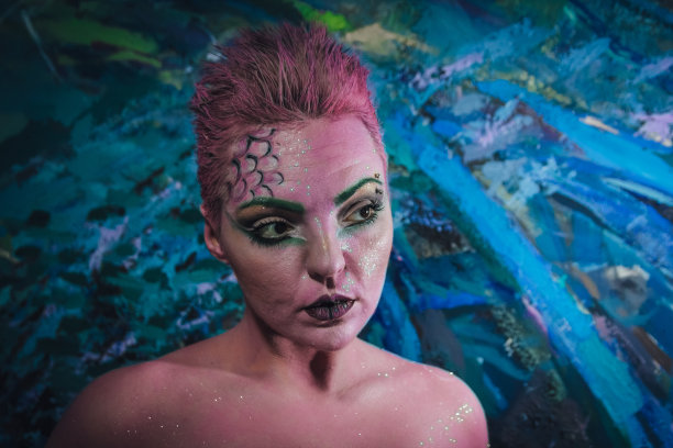 正面的女人肖像与创造化妆，彩色的脸油漆和背景，湿头发。图片下载