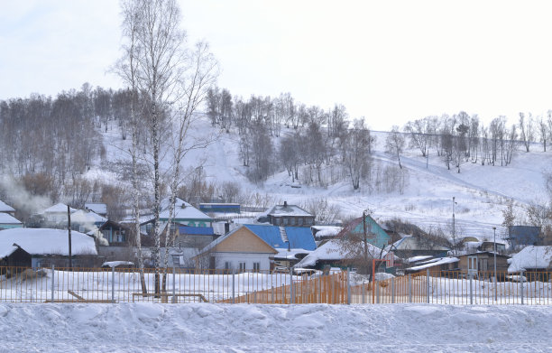 雪山背景上的乡村房屋。冬天的风景。图片下载