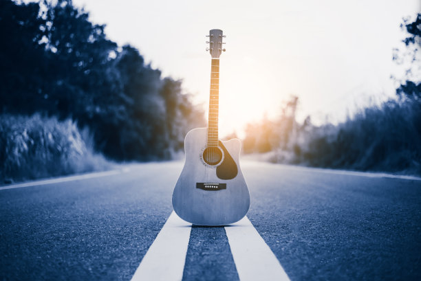 木吉他躺在街道上，以日出为背景，音乐理念之旅图片下载