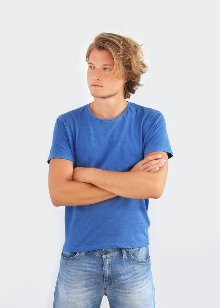 一个迷人的少年站在灰色墙壁前的肖像。图片下载