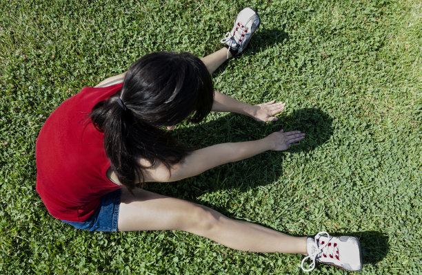 西班牙少女坐在绿色草地上伸展图片下载
