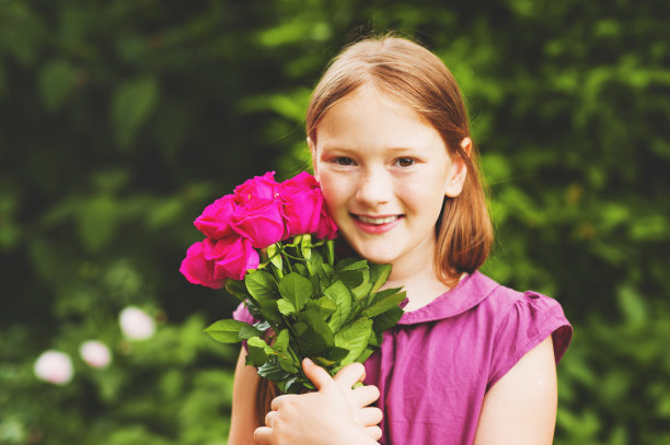 一个8-9岁的可爱小女孩的肖像，拿着一束漂亮的粉红色玫瑰图片下载