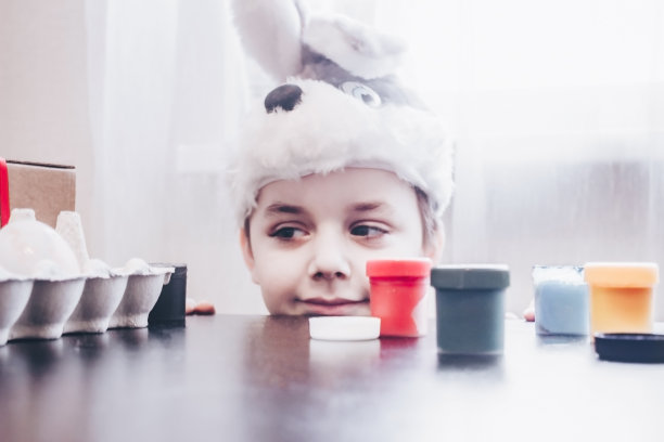 为了庆祝复活节，小男孩用颜料画彩蛋图片下载