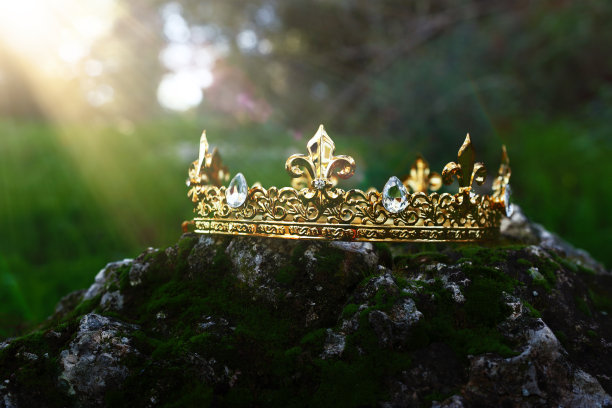神秘而神奇的金冠照片，上面的石头覆盖着苔藓，在英格兰的树林或田野景观中闪耀着光芒。中世纪的概念。图片下载