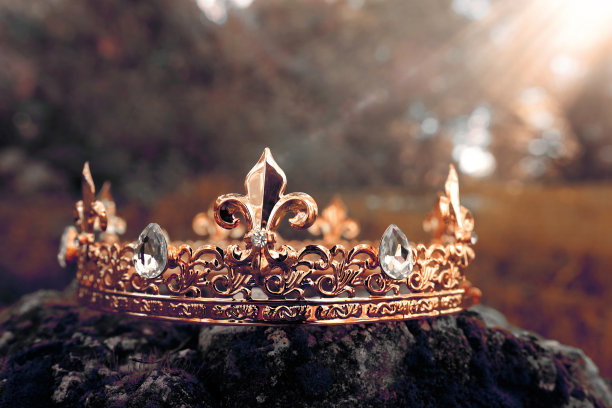 神秘而神奇的金冠照片，上面的石头覆盖着苔藓，在英格兰的树林或田野景观中闪耀着光芒。中世纪的概念。健美过滤。图片下载