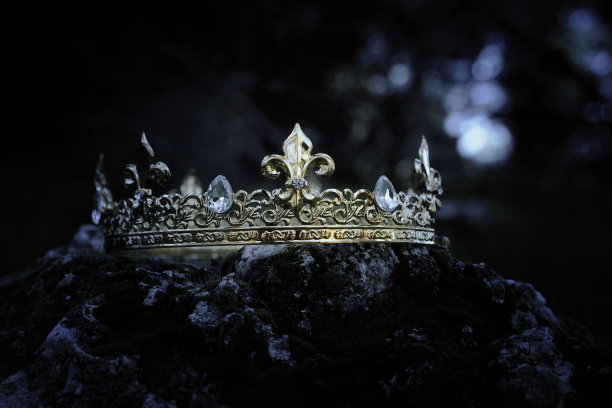 神秘而神奇的金冠照片，上面的石头覆盖着苔藓，在英格兰的树林或田野景观中闪耀着光芒。中世纪的概念。图片下载