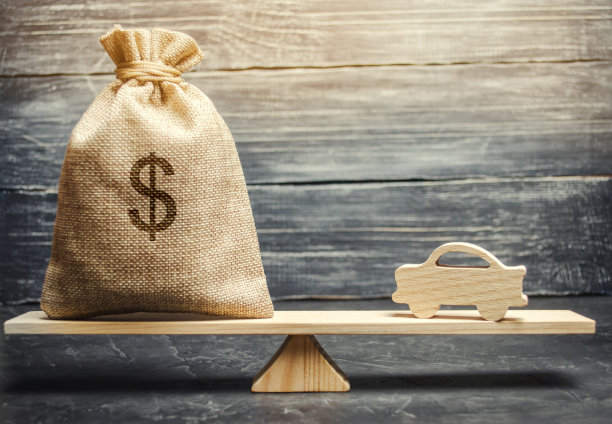 一个钱袋，秤上有一辆微型木车。汽车保险。攒钱买车。为梦想存钱。购买汽车。图片下载