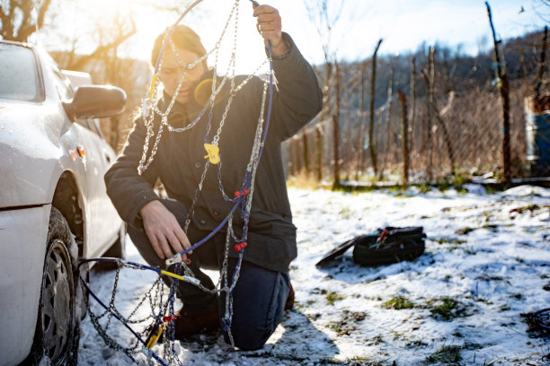 中年男子准备在汽车轮胎上定位轮胎链图片下载