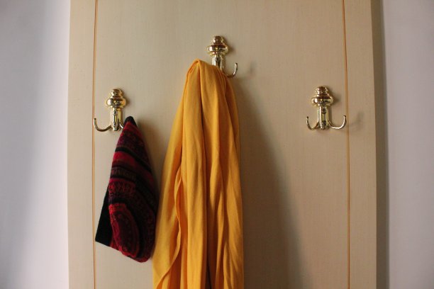 奶油木镶板上的金色外套挂钩图片下载