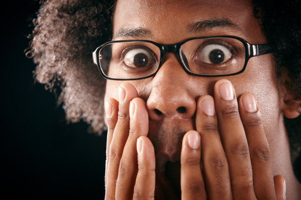 震惊的年轻人的特写，手对脸图片下载