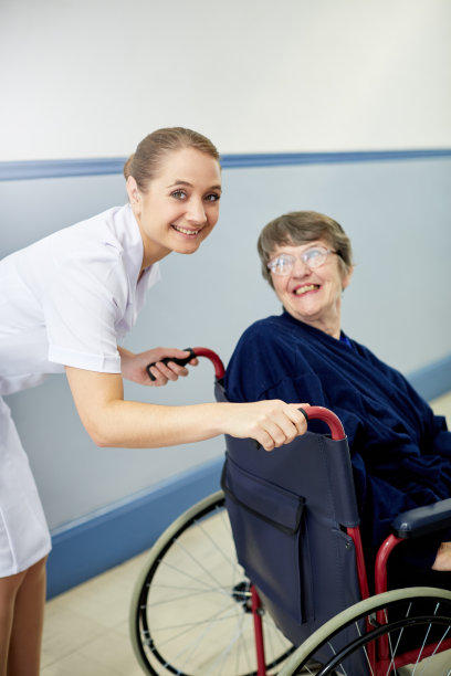 快乐的老年病人在轮椅上转向护士微笑图片下载