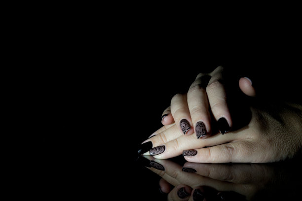 漂亮的美甲，黑色指甲油，特写照片。黑色背景的女性手图片下载