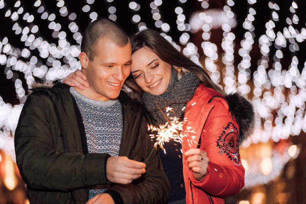 在冬季城市的夜晚，情侣们拿着烟花图片下载