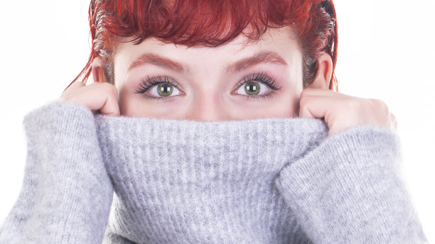 近距离的肖像年轻女子覆盖脸与高领和看镜头图片下载