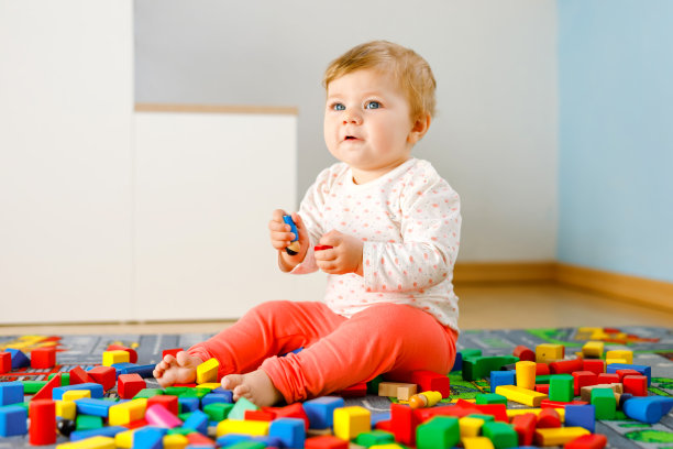 可爱的小女孩玩益智玩具。快乐健康的孩子在家庭的房间里玩彩色不同的积木。婴儿学习颜色和形式图片下载