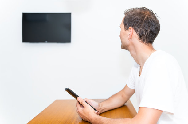 现代房中近距离用房间木桌或写字台安装了小电视和快乐的年轻人拿着遥控器图片下载