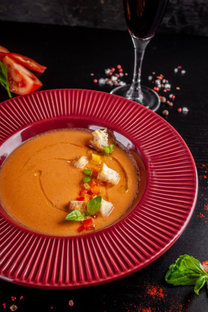 西班牙菜的概念。新鲜西红柿做成的西班牙凉菜汤。在一家餐馆里，黑色的桌子上，红色的盘子里盛着漂亮的菜肴。的背景图片。本空间图片下载