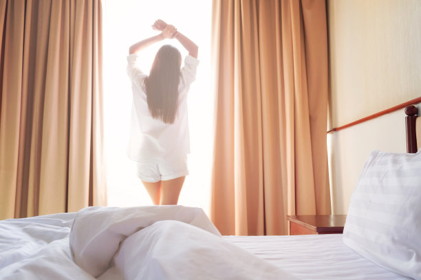 女人醒来后在床上伸懒腰。图片下载