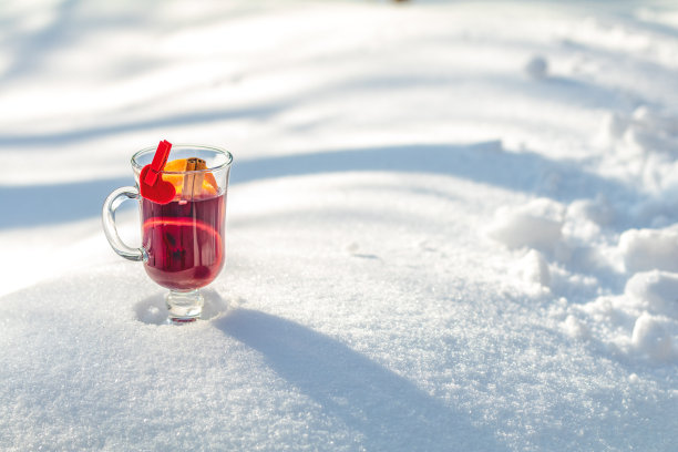 杯中有美味的热葡萄酒和香料，盖在雪地上图片下载